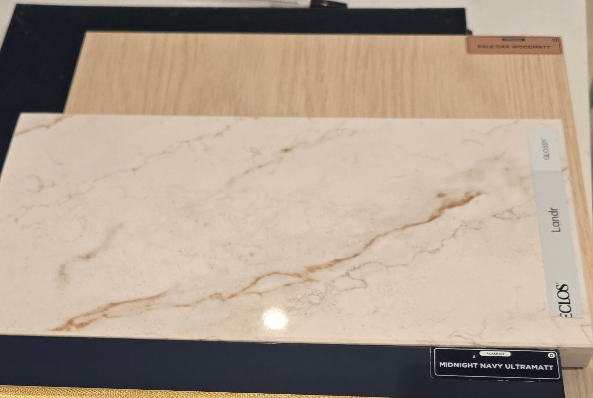 Sample board with a veined stone benchtop, pale oak and midnight navy joinery